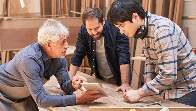 © Robert Kneschke - Adobe Stock Ausbilder mit zwei Azubis in einer Tischlerei