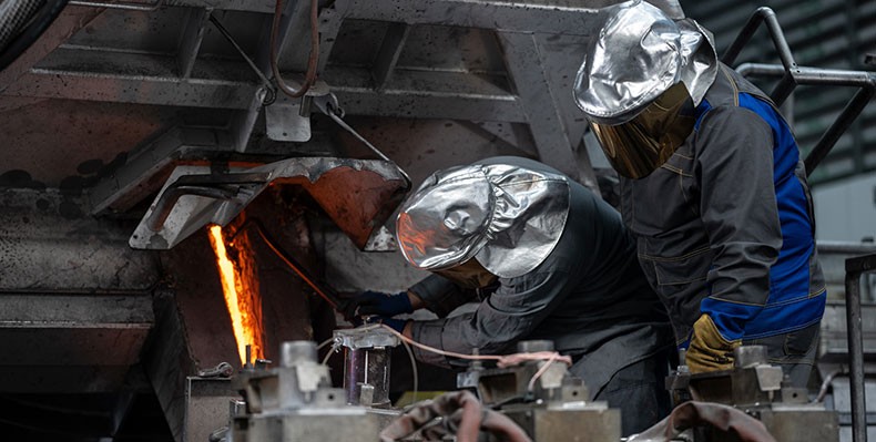 Menschen in Schutzkleidung bei Metallbearbeitung