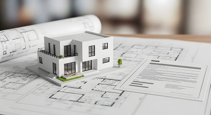 Architektur-Modell eines modernen Hauses mit Konstruktionsplänen auf einem Holztisch